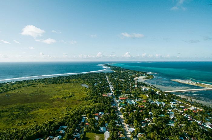 Vue aérienne de l'île voisine  de Hulumeedhoo, 3700 habitants, 5ème plus grande île des Maldives. On loin, on aperçoit l'île - hôtel South Palm Resort